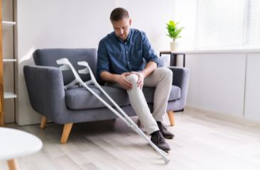 man recovering from injury sitting with crutches