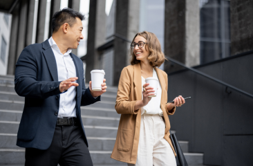 Two people walking and talking with take away coffees